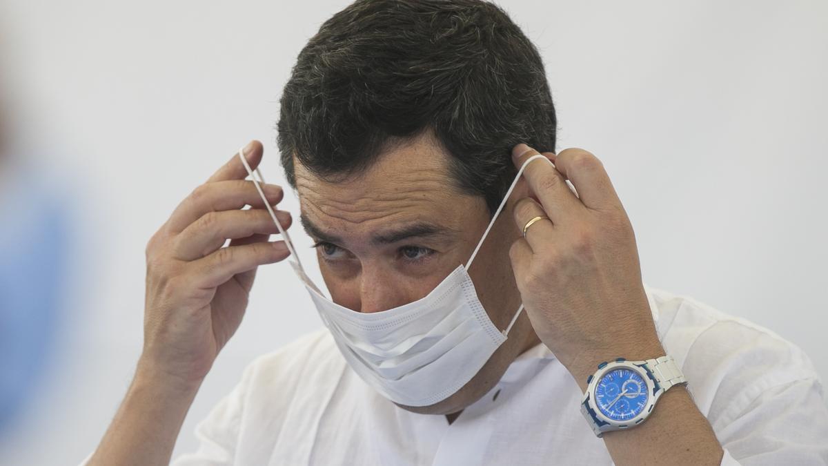 El presidente de la Junta de Andalucía, Juanma Moreno, colocándose una mascarilla.
