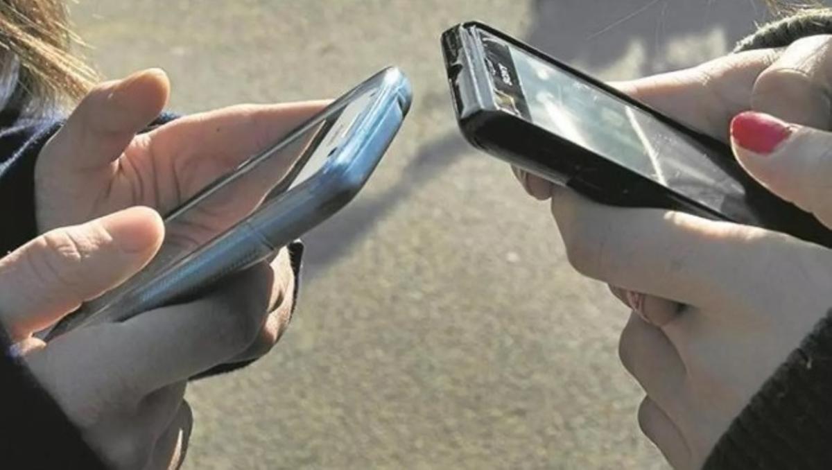 Dos jóvenes utilizan sus móviles.