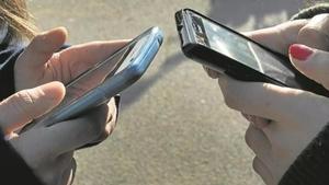 Dos jóvenes utilizan sus móviles.