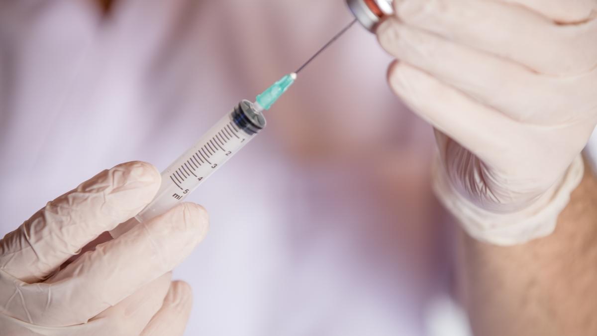 Un sanitario se dispone a administrar una vacuna.