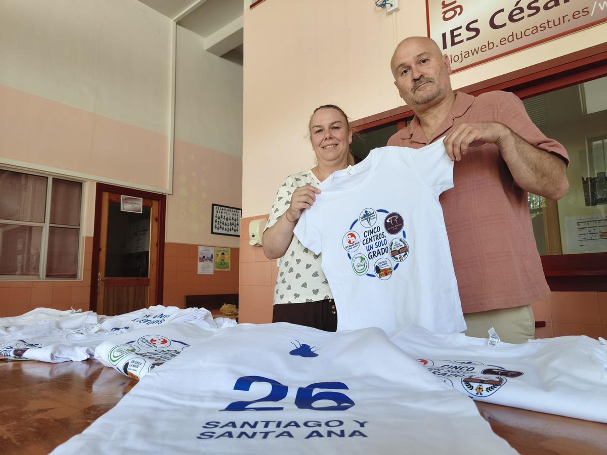 La directora de la Escuela Rural de La Mata, María Alonso, y el director del IES César Rodríguez, Daniel Menéndez, con las camisetas que lucirán los 600 integrantes de la carroza "Cinco centros, un solo Grado".
