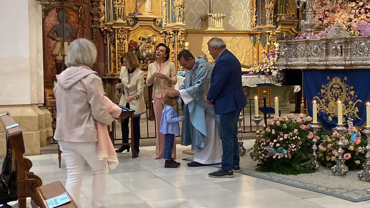 Dos hermanas, una de tres años y otra en brazos de su abuela, también recibían la medalla de las azules por parte del párroco José Sánchez al que acompañaban la camarera de la Dolorosa y el presidente del Paso Azul.