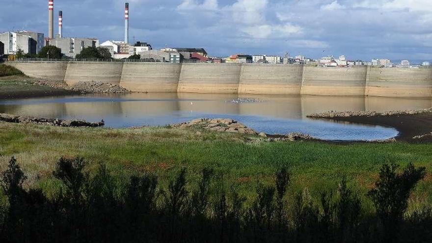 El embalse de Meicende, con el caudal bajo en 2017, con industria y viviendas detrás.