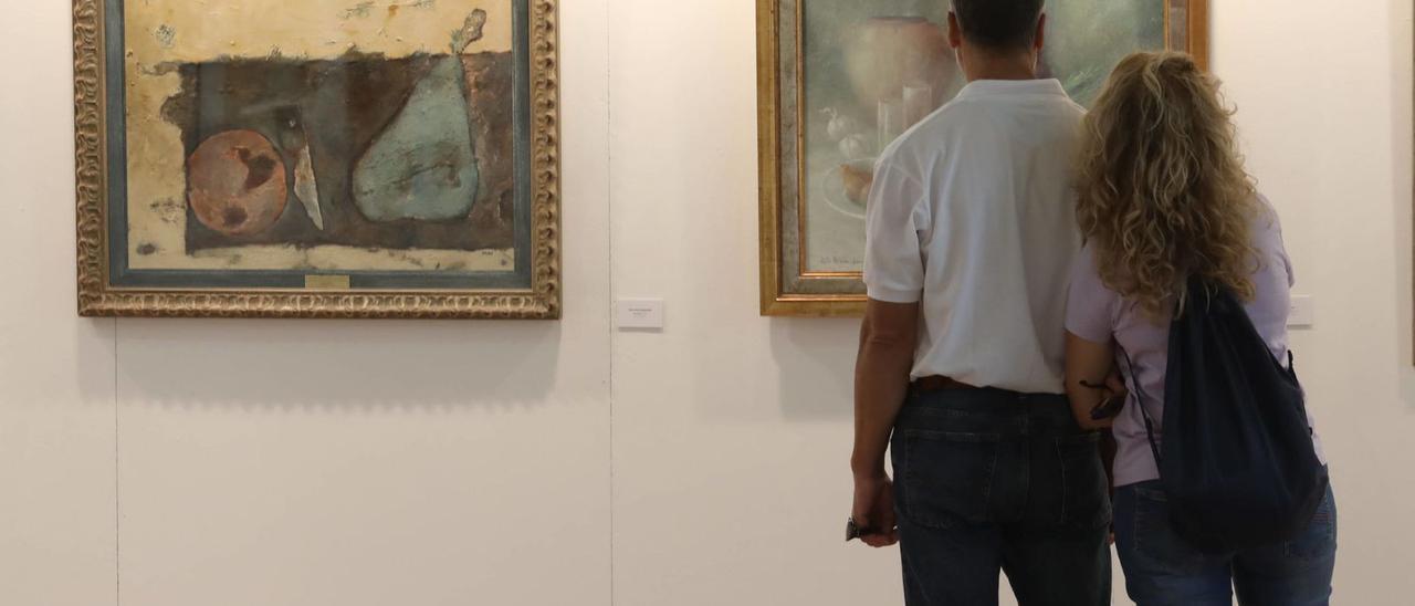 Una pareja admira los cuadros de la exposición de Casa Consuelo, en la plaza de Trascorrales. | Luisma Murias