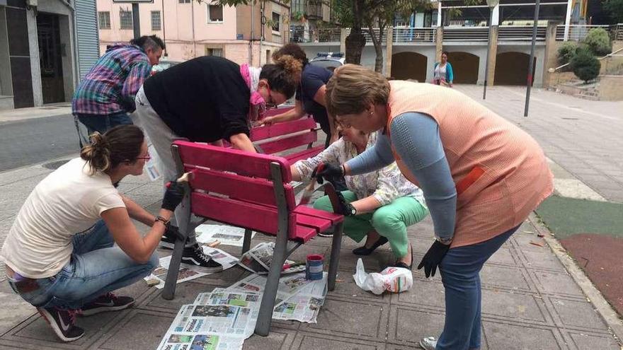 Mujeres de San Martín del Rey Aurelio, pintando de rosa los bancos de la plaza de Ramón y Cajal.