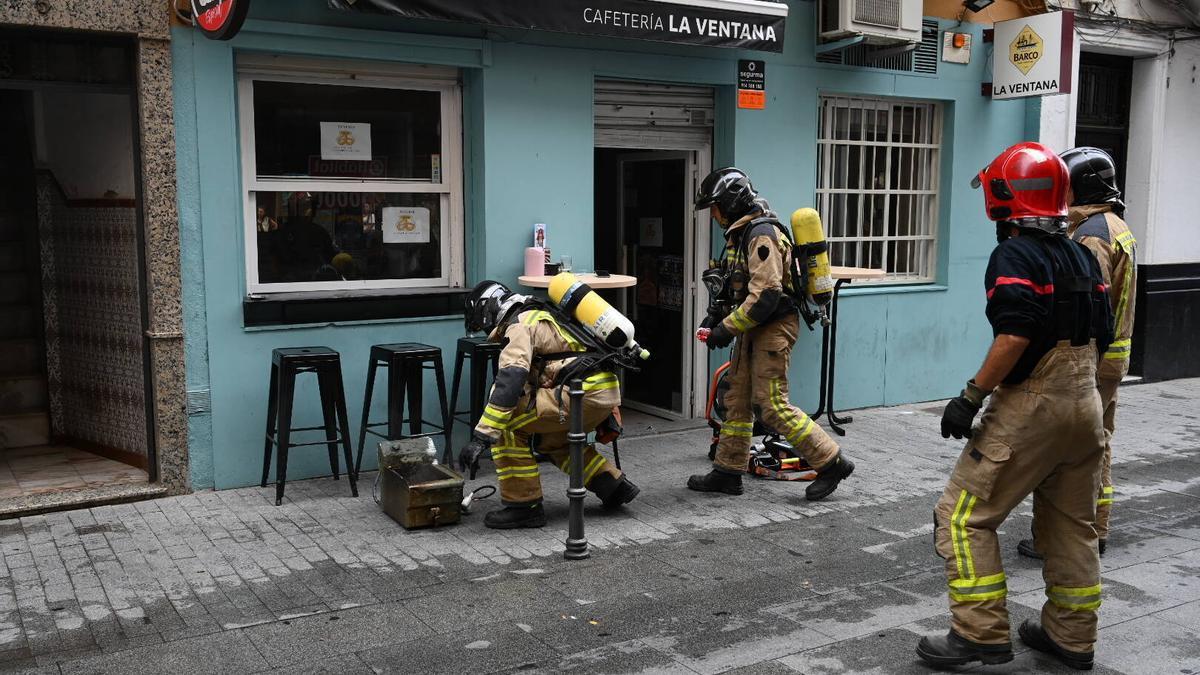 Los bomberos en el exterior en el bar de Vasco Núñez, con la freidora donde se ha originado el fuego en el suelo.