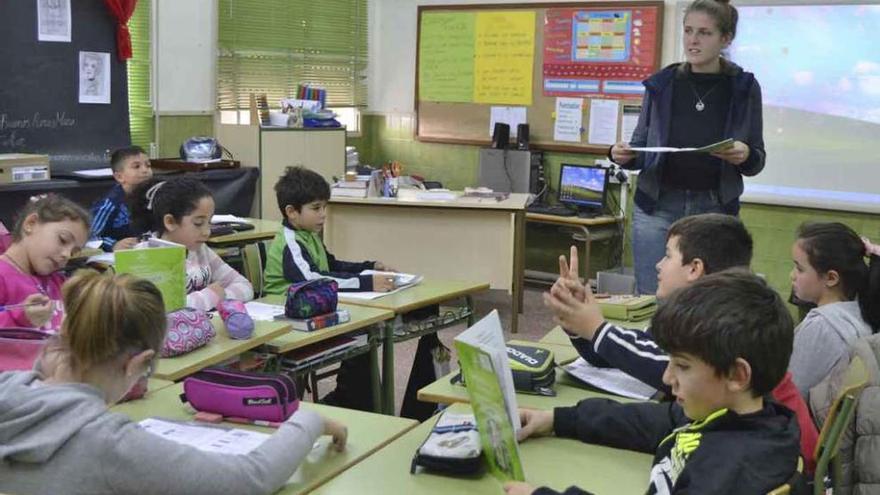 Una de las monitoras de inglés lee en voz alta junto a escolares de Benavente.