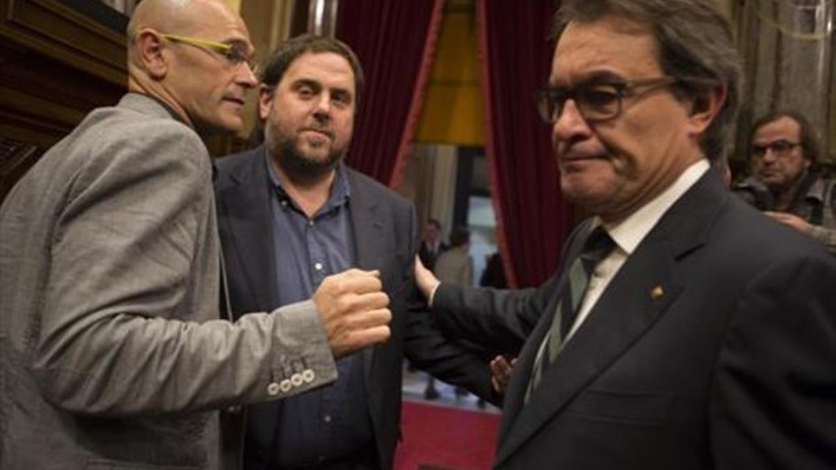 Raül Romeva, Oriol Junqueras y Artur Mas se saludan al terminar la sesión matinal del Parlament de ayer.