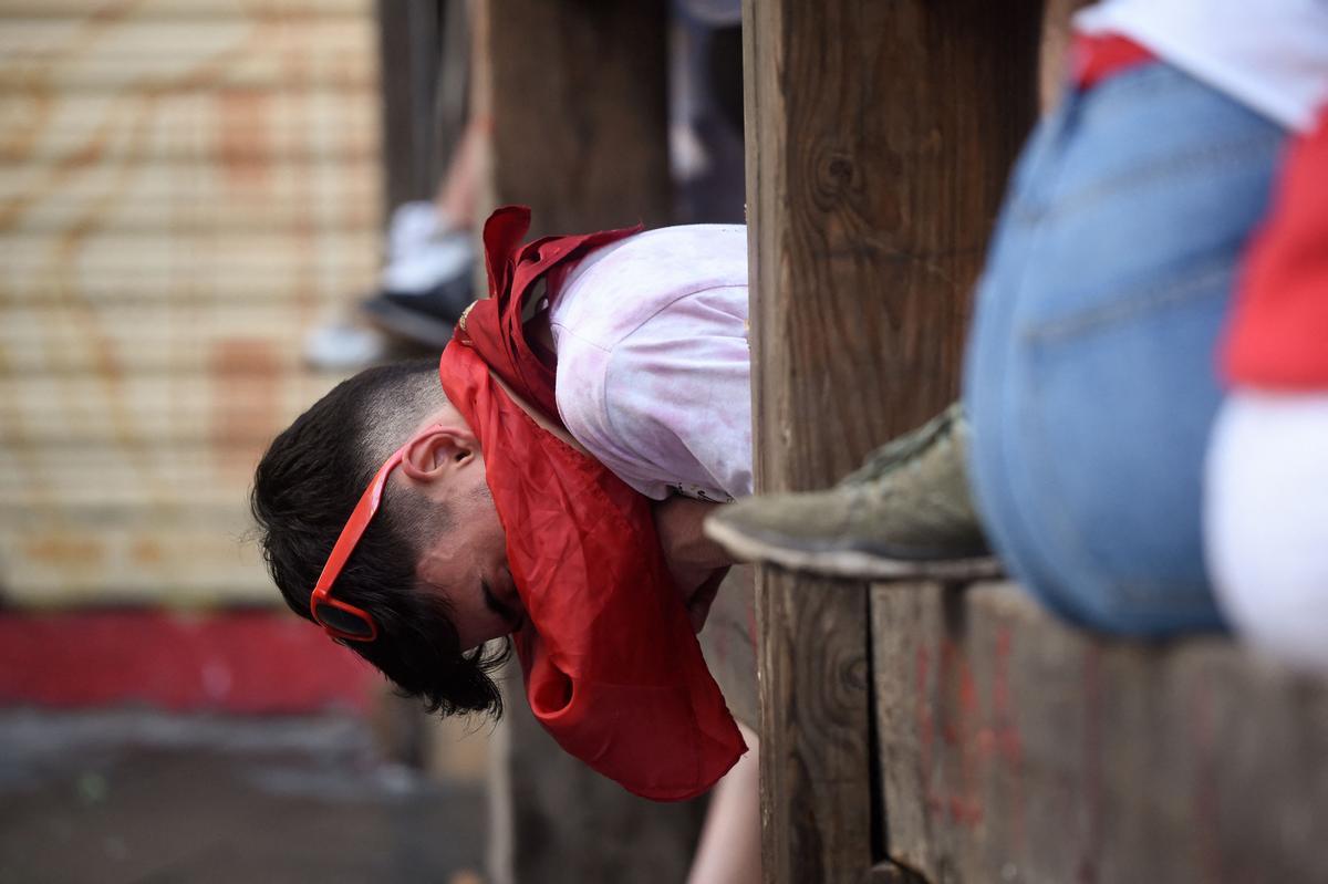 Un participante descansa en una valla durante el encierro (corrida de toros) de las fiestas de San Fermín en Pamplona.