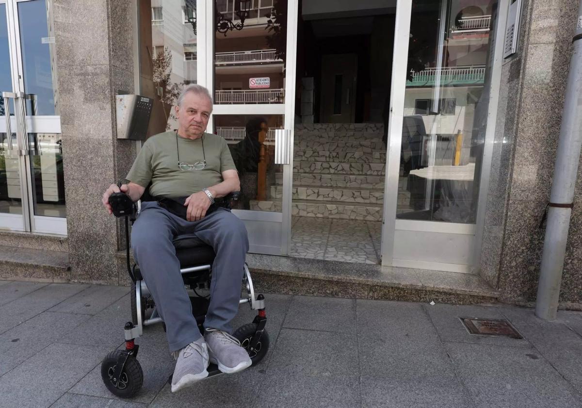 Manuel Martínez, frente al portal de su edificio, con el ascensor y las escaleras al fondo.