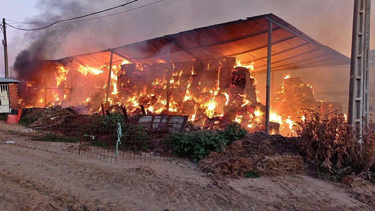 Pacas de forraje bajo una tenada ardiendo en la madrugada de ayer en una nave de El Maderal. | Cedida