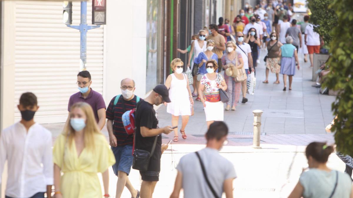 Varias personas pasean con mascarilla por el centro de Alicante