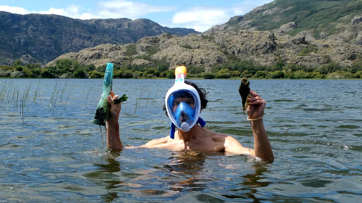 Un voluntario enseña los residuos recogidos del fondo del Lago