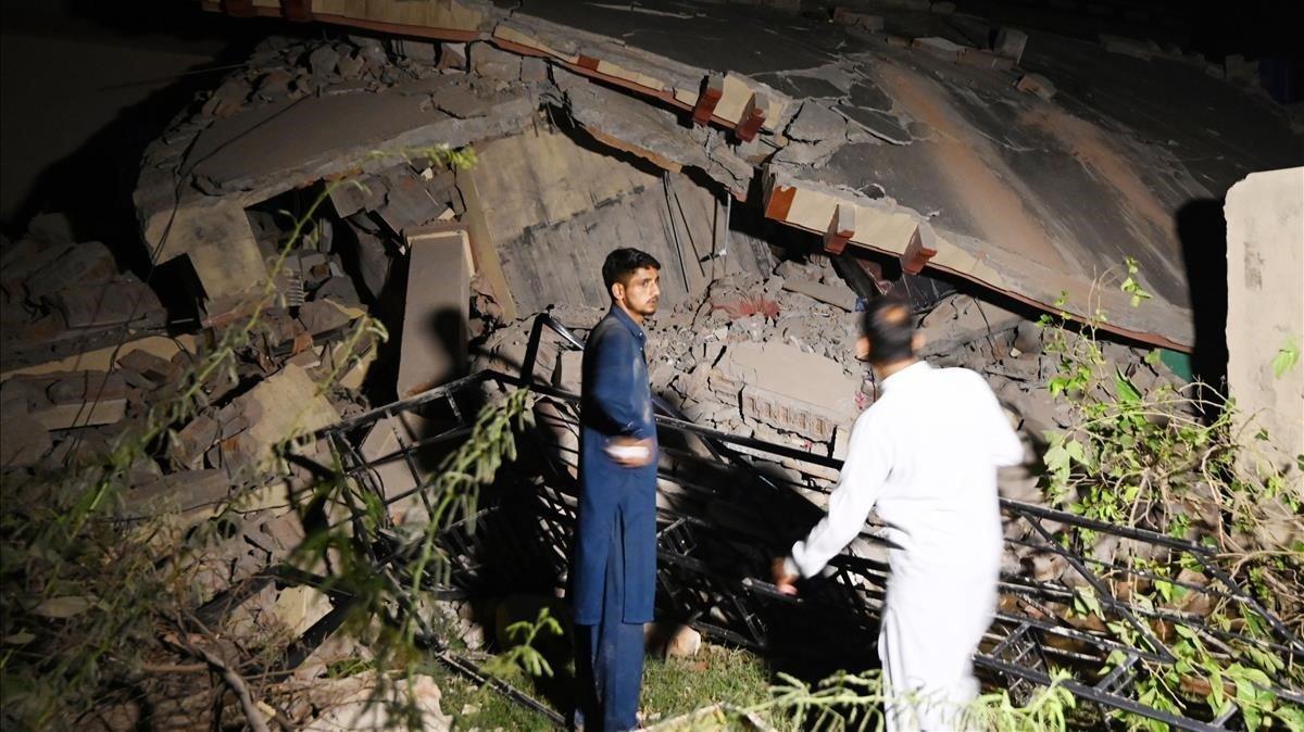 zentauroepp50034361 pakistani men stand beside a collapsed building following an190924185835