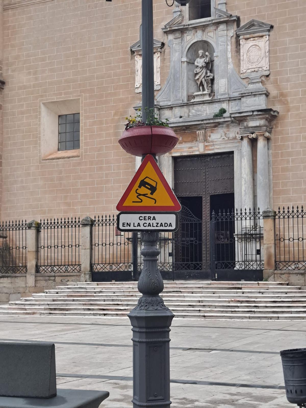 Señal que alerta sobre la presencia de cera en la calzada instalada en la plaza de España de Badajoz.