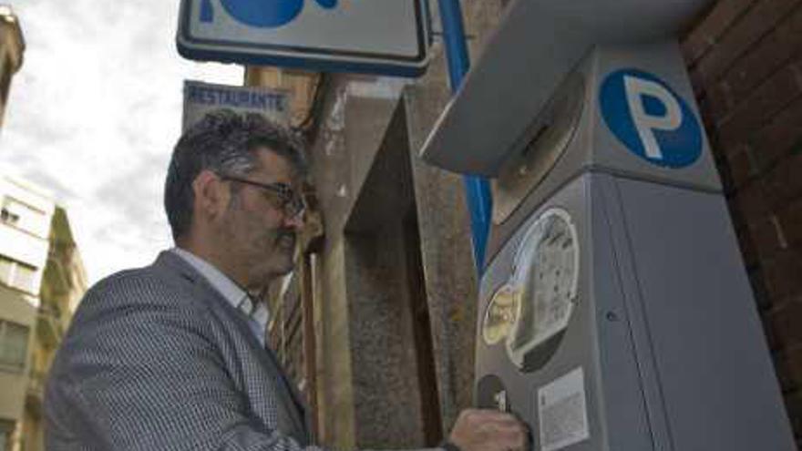 Un hombre saca un ticket de un parquímetro.