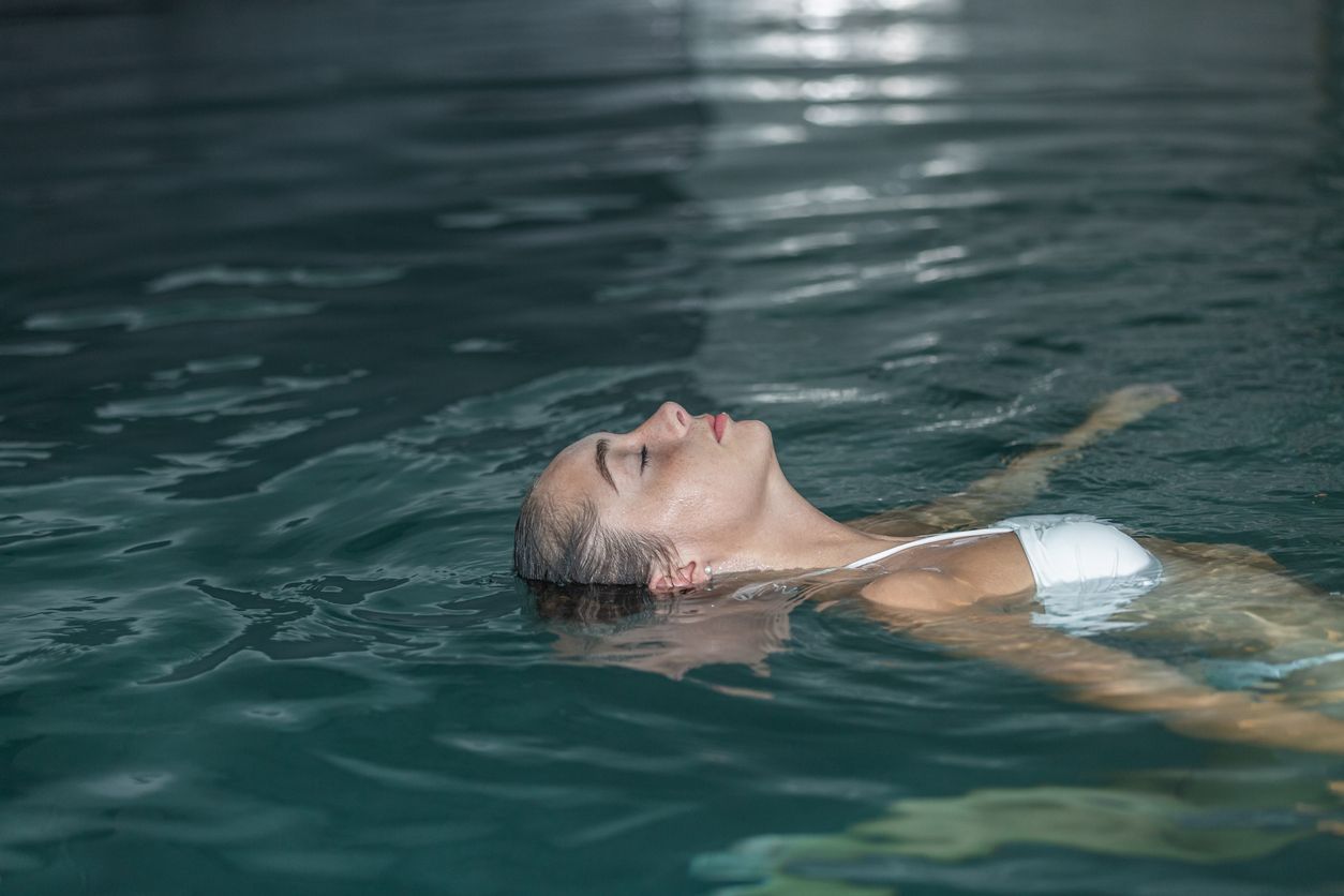 Mujer joven flotando en el agua de la piscina.