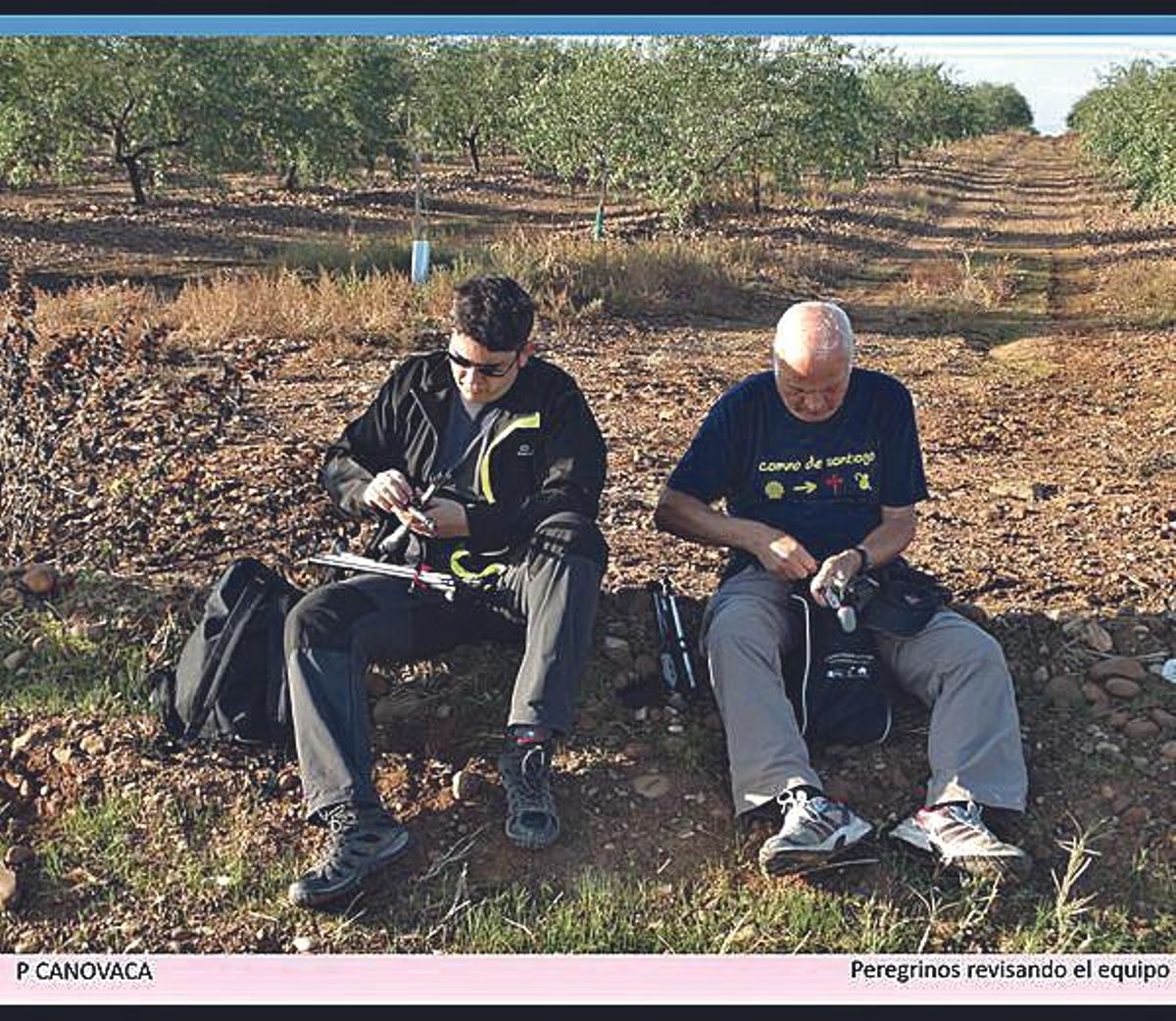 Peregrinos en el camino revisando su equipaje y calzado.