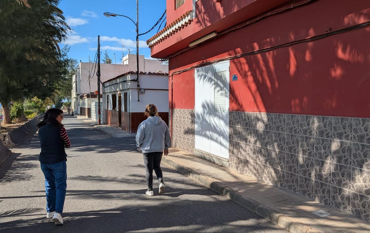 Vecinos de Juan Grande pasan junto al antiguo local donde estaba la farmacia, hoy reconvertido en vivienda.