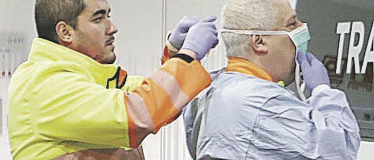 Un sanitario, colocando a otro el traje de protección, anoche en el HUCA.