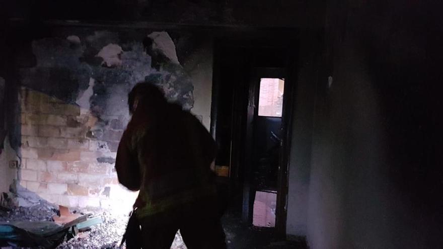 Los bomberos, durante su actuación en el interior de la vivienda siniestrada en Carlet.