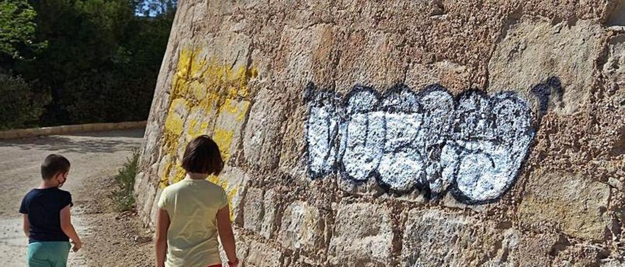 Dos niños pasan por delante del torreón pintarrajeado.