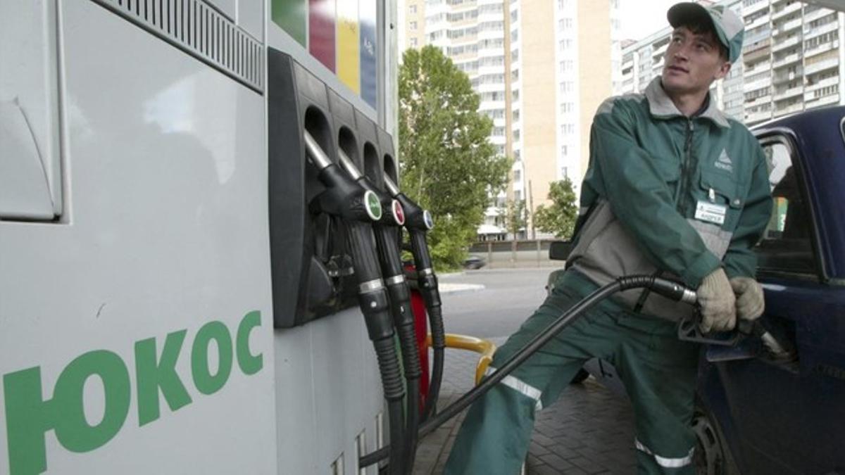 El empleado de una gasolinera de la empresa Yukos en Moscú pone combustible a un coche.