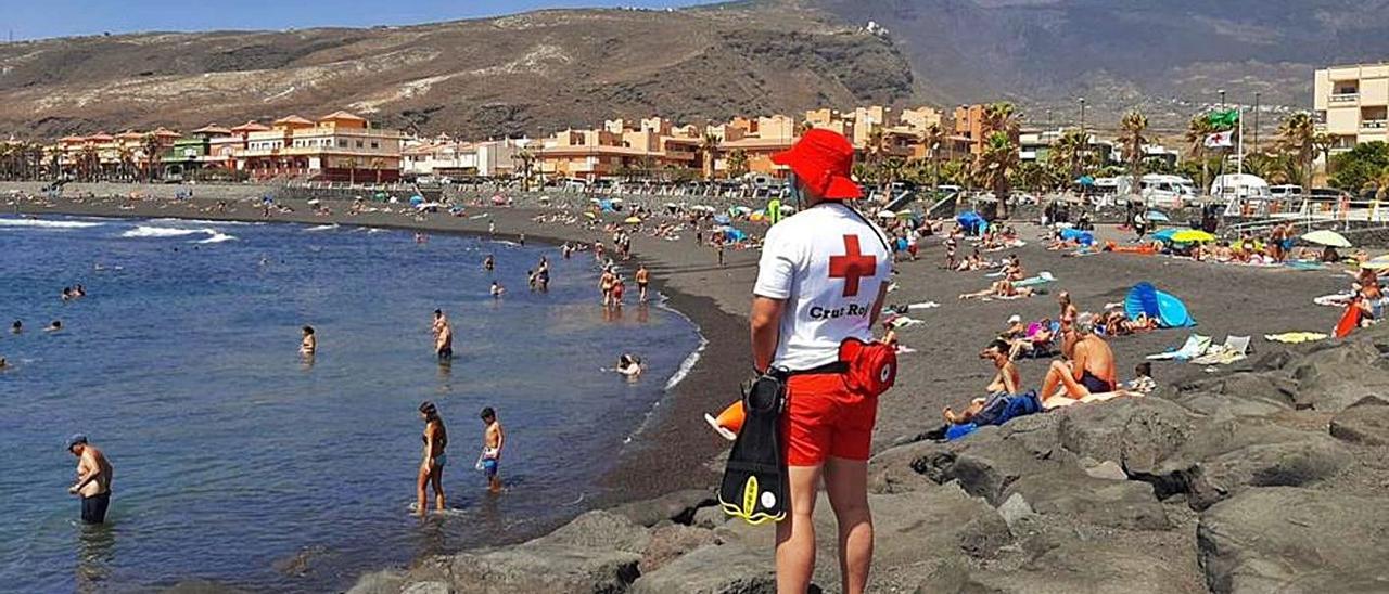 Un voluntario de Cruz Roja supervisa los movimientos de unos bañistas desde una zona elevada.