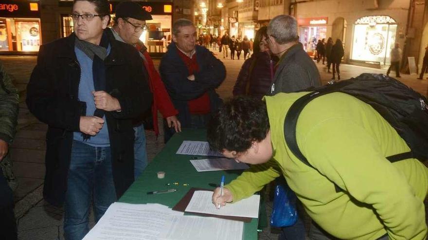 Un grupo de vecinos firma la iniciativa en una mesa situada en la Praza da Peregrina.  // Rafa Vázquez