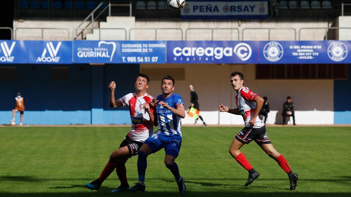 Ross disputando un balón aéreo con Natalio con Piay en segundo término.