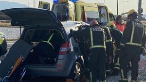 Bomberos trabajan en el rescate de los pasajeros del turismo que han quedado atrapados en el accidente. 