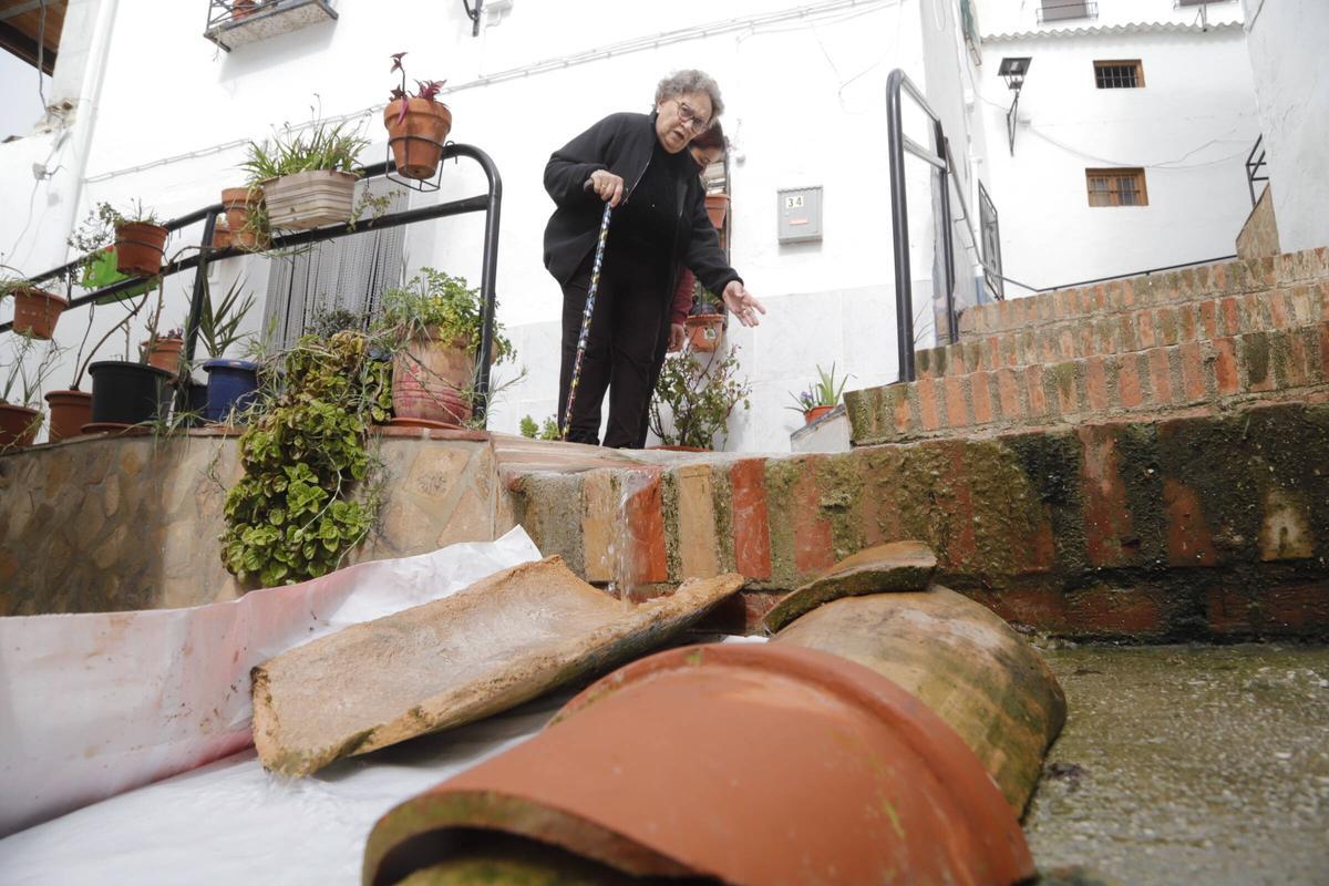 María, vecina de El Higueral, señala el punto por donde empezó a salir el agua desde una vivienda a la calle.