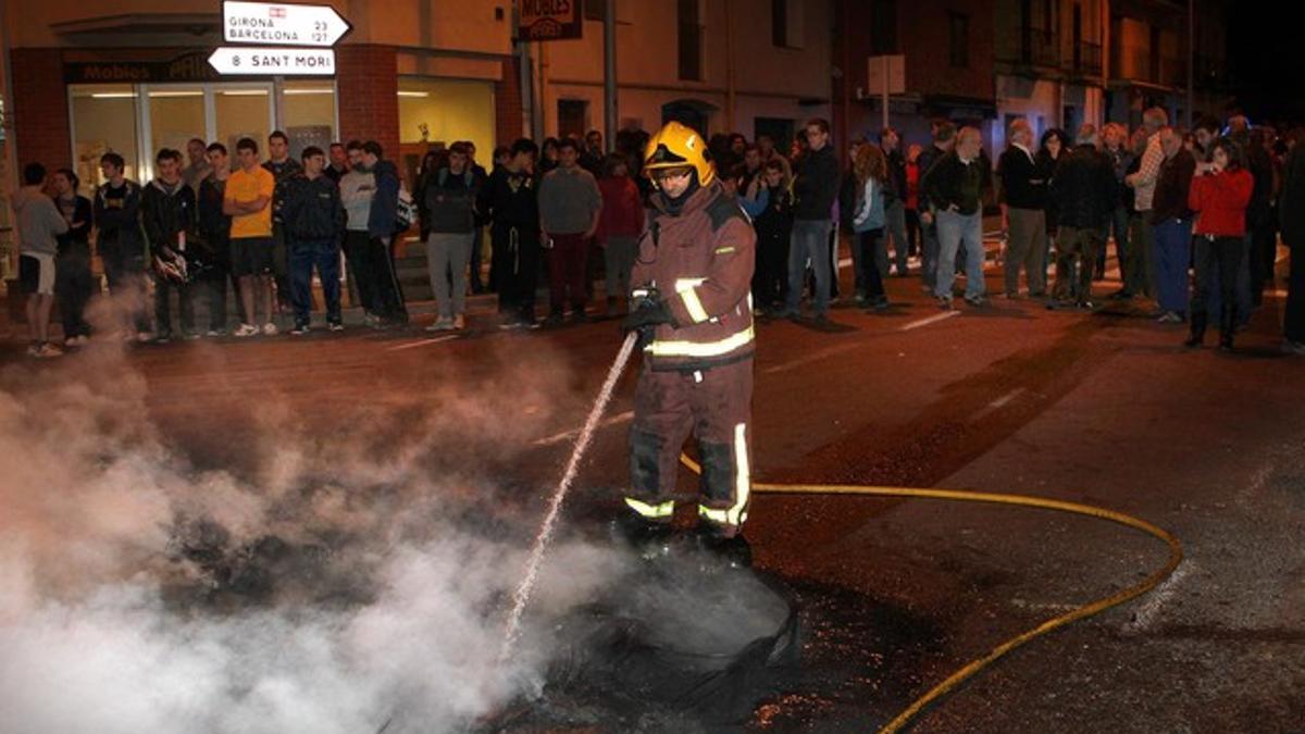 Un bombero apaga el fuego encendido por los vecinos de Bàscara por la alta siniestralidad de la N-2, anoche.