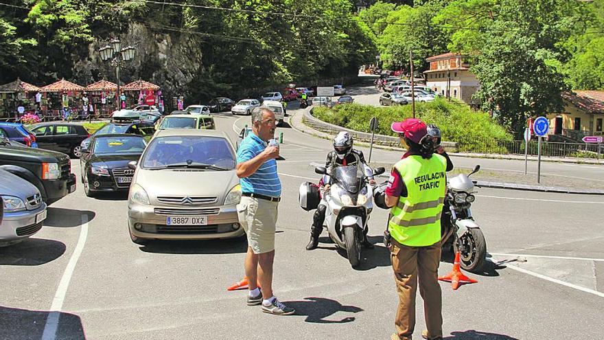 Una reguladora, ayer, explicando a varios visitantes el cierre momentáneo de la carretera de los Lagos.