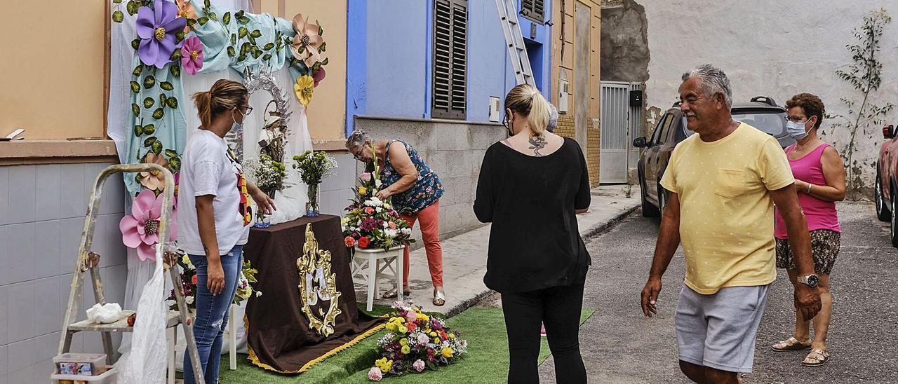 Nayra Samper, de espaldas, trabaja junto a su familia en su altar doméstico del Carmen. | | JOSÉ CARLOS GUERRA