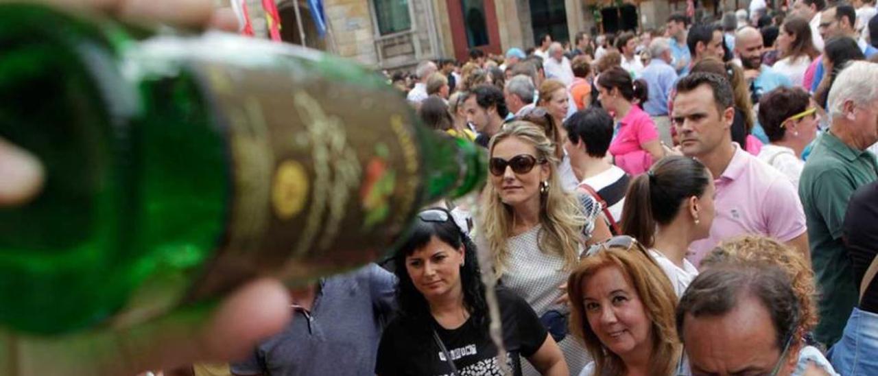 gran ambiente. A la derecha, arriba, el niño Álvaro Díaz escancia un culín en Sidra Buznego; debajo, la gente espera para tomar un culín en uno de los puestos. Bajo estas líneas, unos vecinos comen en los soportales de la plaza; a la derecha, la Banda &quot;Villa de Xixón&quot; toca para el gentío.