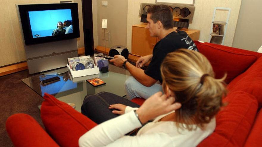 Una pareja ve la televisión en su salón.