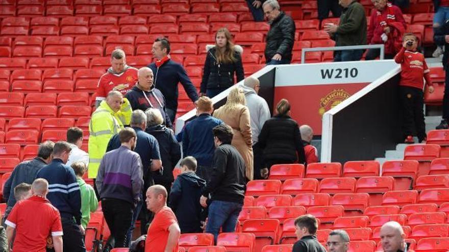 Aficionados del Manchester United abandonan el estadio Old Trafford tras confirmarse la suspensión del encuentro.