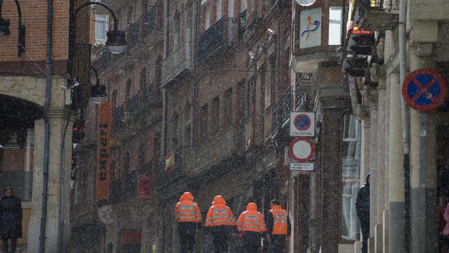 Miembros de Protección Civil caminan por la Rúa durante un chubasco  la tarde del domingo.