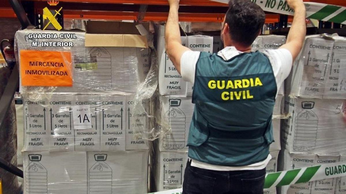 Un agente de la Guardia Civil inspecciona el aceite intervenido.