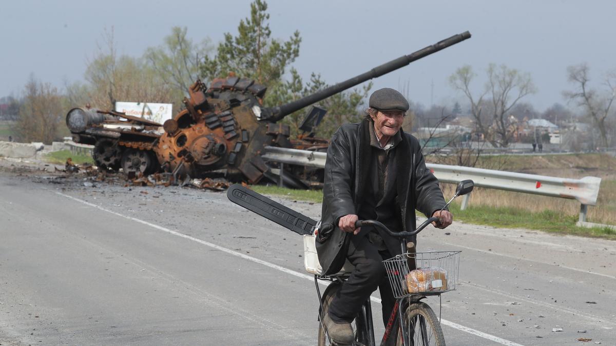 Un hombre pasa en bici junto a un tanque destruido en las afueras de Kiev.