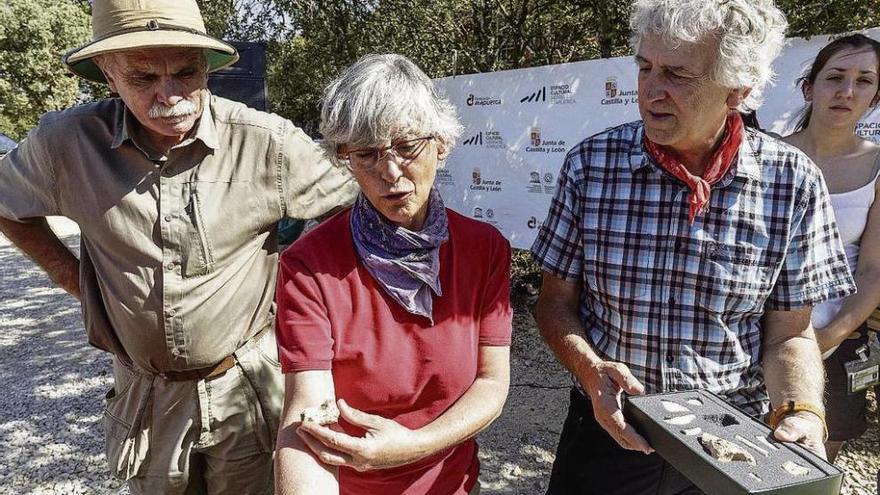 Los codirectores de los yacimientos de Atapuerca Eudald Carbonell (izda.) y Juan Luis Arsuaga (dcha.), junto a una de las investigadoras, que muestra un hueso fósil.
