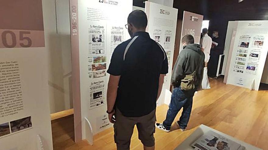 Higinio Alonso, a la izquierda, y  Fabián Díez observan dos de los paneles de la exposición “Seguimos dando tira”, ayer, en el centro cultural de Moreda. | A. Velasco