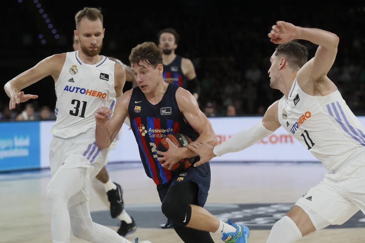 SEVILLA, 25/09/2022.- El base lituano Rokas Jokubaitis (c), del Barcelona, penetra ante la defensa del alero bosnio Dzanan Musa (i) y el alero croata Mario Hezonja (d), del Real Madrid, durante la final de la Supercopa Endesa entre el Real Madrid y el FC Barcelona, disputada este domingo en el pabellón de San Pablo de Sevilla. EFE/ Jose Manuel Vidal