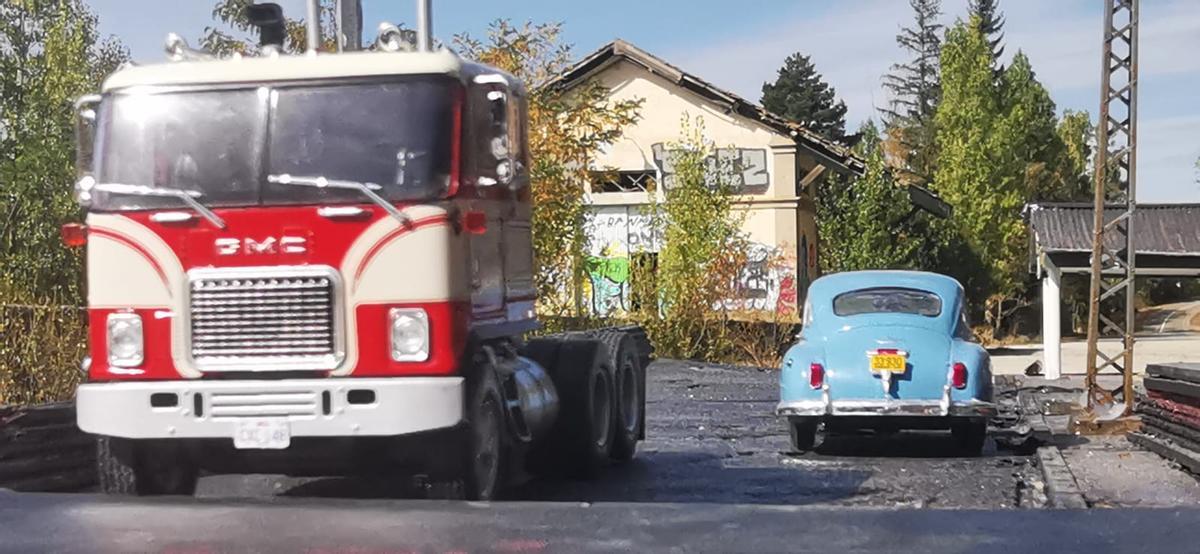 Maqueta de una gasolinera con un camión y un vehículo clásicos.