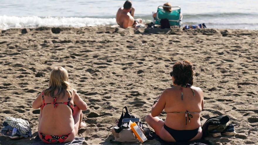 Varias personas toman el sol en la playa de la Malagueta.