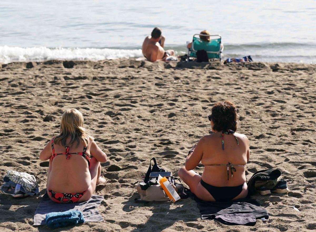Varias personas toman el sol en la playa de la Malagueta. | ÁLEX ZEA