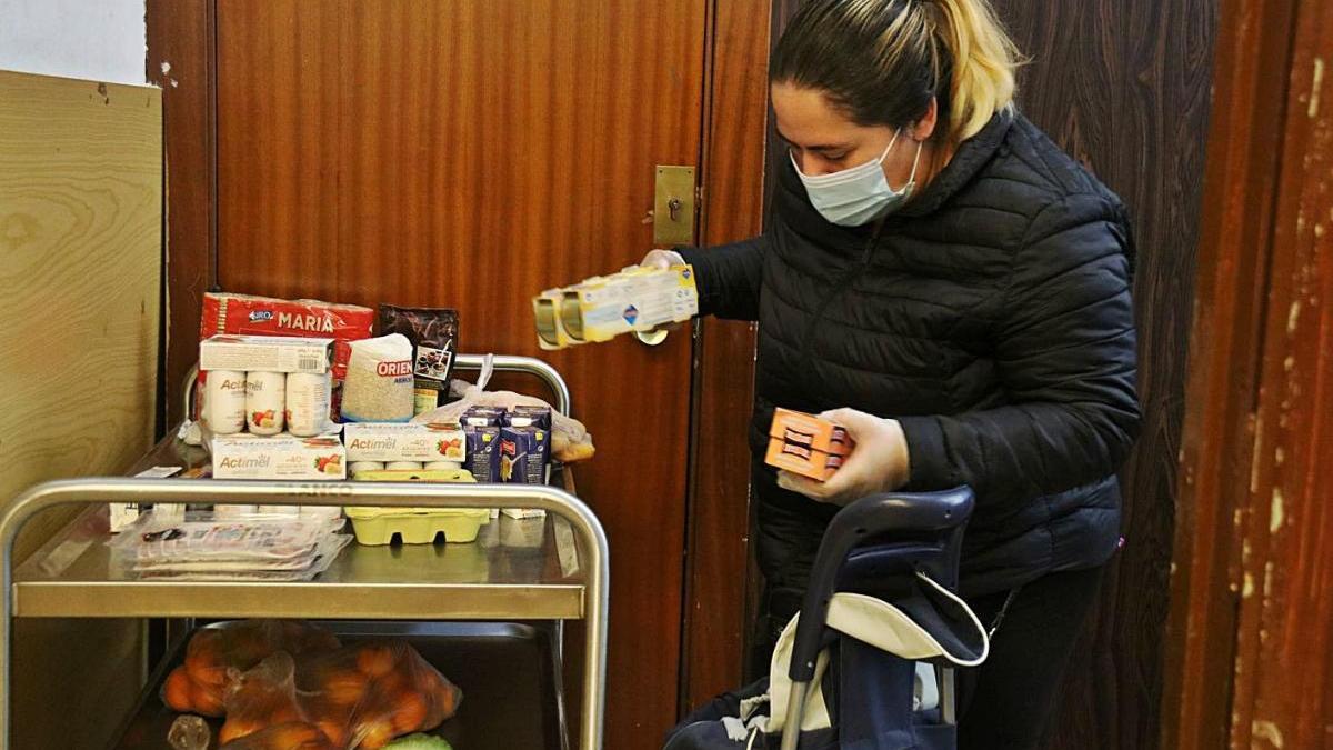 Una dona omple un carro d&#039;aliments en un punt de distribució de Càritas a Barcelona