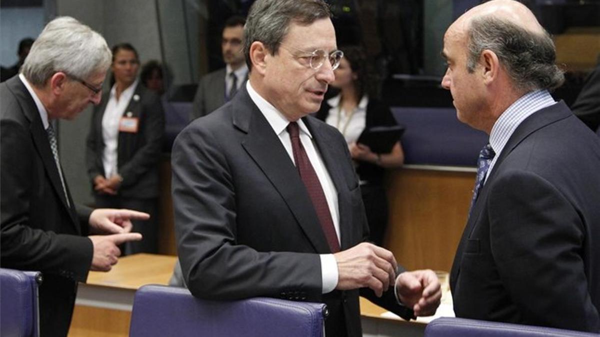 El ministro de Economía, Luis de Guindos, conversa en la reunión del Eurogrupo con el presidente del Banco Central Europeo, Mario Draghi.