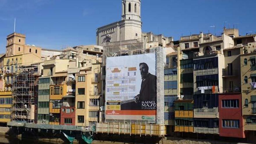 La façana recoberta amb la lona i amb la Catedral al fons.